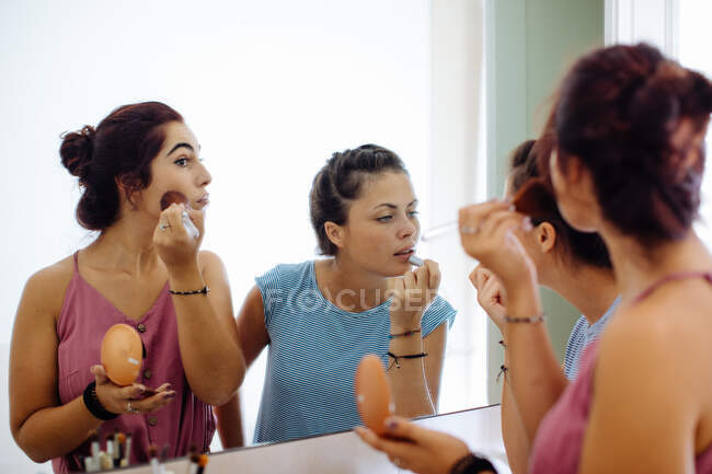 Amigos poniéndose maquillaje en el espejo - foto de stock