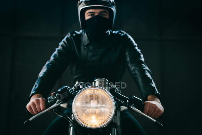 Junger männlicher Motorradfahrer auf Oldtimer-Motorrad in Garage, Portrait — Stockfoto
