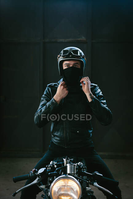 Молодий чоловічий мотоцикліст на старовинному мотоциклі в гаражі, портрет — стокове фото