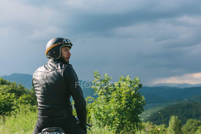 Jovem motociclista do sexo masculino em moto olhando por cima de seu ombro, Florença, Toscana, Itália — Fotografia de Stock