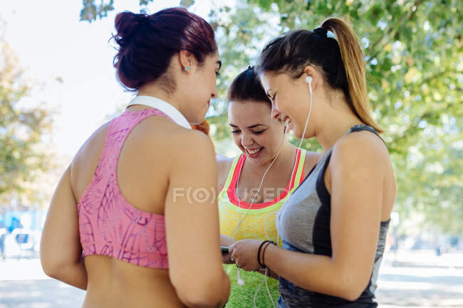 Freunde üben und nutzen Handy im Park — Stockfoto