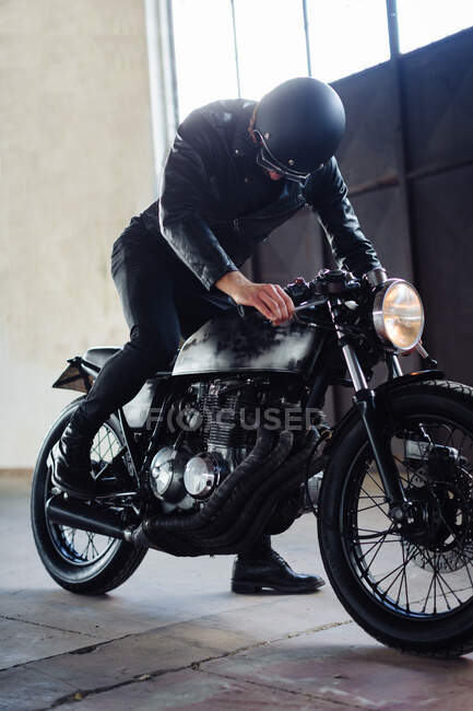 Jovem motociclista do sexo masculino revving motocicleta vintage na garagem — Fotografia de Stock