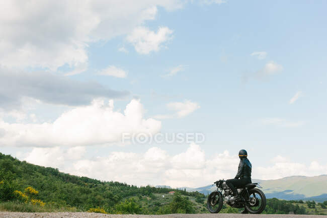 Молодий чоловік - мотоцикліст вінтажного мотоцикла, що дивиться на краєвид Флоренції, Тоскани, Італія. — стокове фото