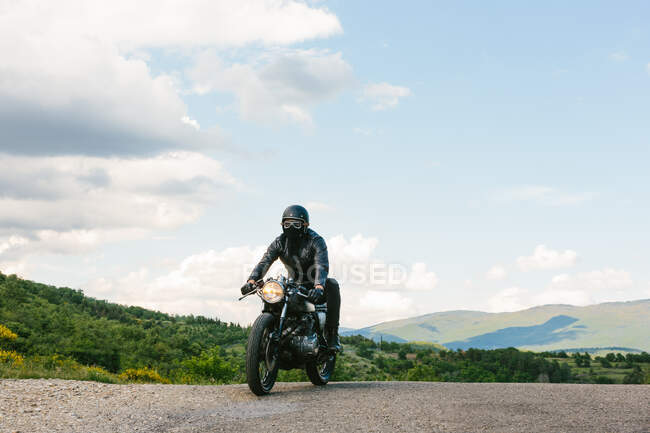 Joven motociclista masculino en motocicleta vintage en carretera rural, Florencia, Toscana, Italia - foto de stock
