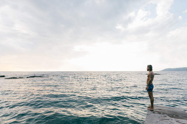 Uomo in piedi sul bordo del mare — Foto stock