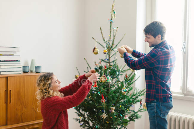 Couple decorating Christmas tree at home — Stock Photo