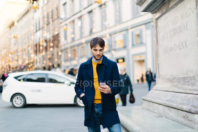 Hombre con smartphone en piazza, Firenze, Toscana, Italia - foto de stock