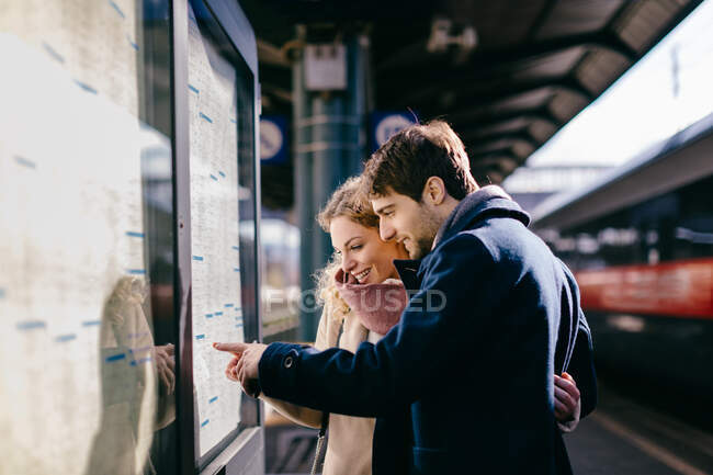 Paar überprüft Fahrplan am Bahnhof, Firenze, Toscana, Italien — Stockfoto