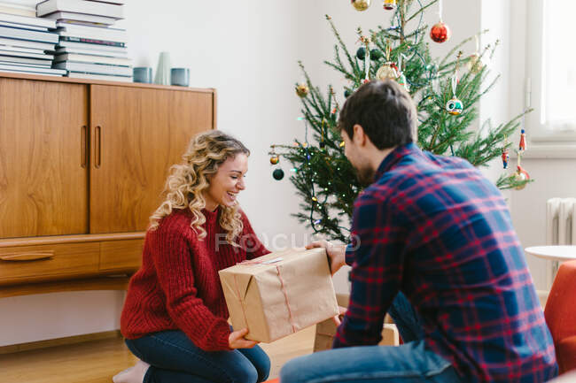 Casal colocando presentes sob a árvore de Natal em casa — Fotografia de Stock