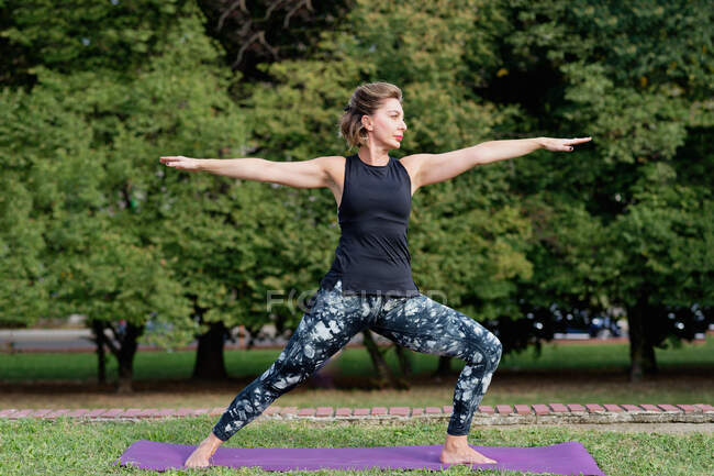 Mature blond woman doing yoga in a park. — Stock Photo