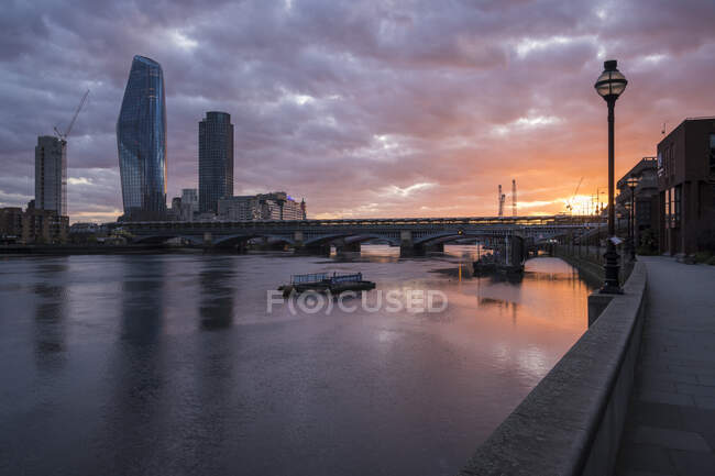 View from Blackfriars Bridge at sunset, River Thames and modern buildings, and the setting sun. — Stock Photo