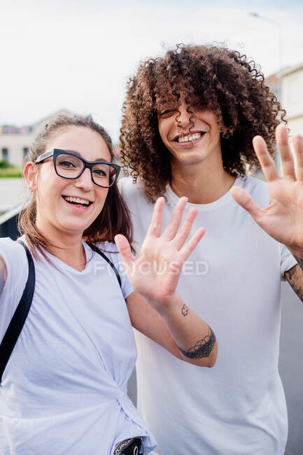 Ritratto di donna e uomo con braccia tatuate, che sorridono e salutano la macchina fotografica. — Foto stock