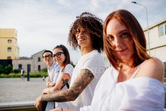 Mixed race group of friends hanging out together in town. — Stock Photo