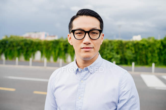 Портрет мужчины в светло-голубой рубашке и очках, смотрящего в камеру. — стоковое фото