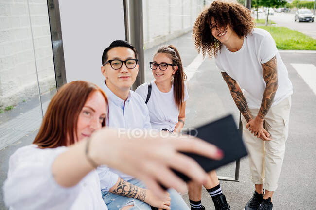 Смешанная расовая группа друзей тусуется вместе в городе, делая селфи с мобильного телефона. — стоковое фото