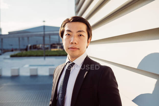 Porträt eines asiatischen Geschäftsmannes im dunklen Anzug, der in die Kamera blickt. — Stockfoto