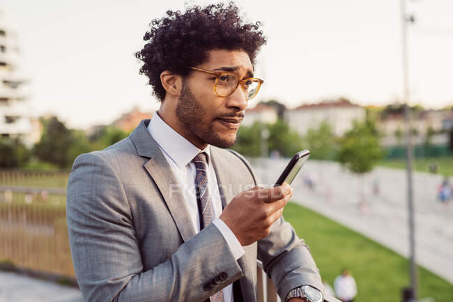 Портрет бизнесмена в очках и сером костюме, с помощью мобильного телефона. — стоковое фото