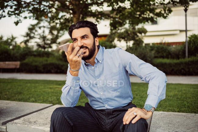 Retrato de empresário barbudo vestindo camisa azul, usando telefone celular. — Fotografia de Stock