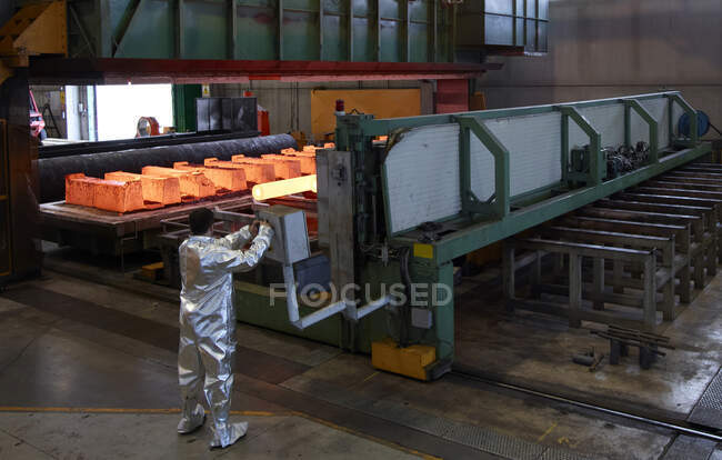 Hombre con traje de protección contra el calor plateado trabajando en una fábrica de acero. - foto de stock