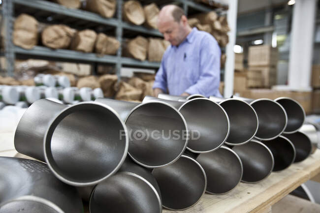 Uomini che lavorano in una fabbrica di acciaio, tubi d'acciaio corti sugli scaffali. — Foto stock