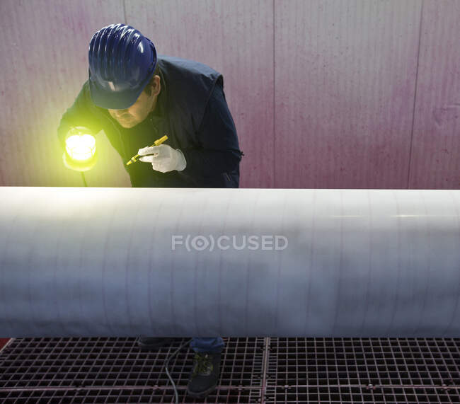 Uomo che lavora in una fabbrica di acciaio, ispezionando tubo di acciaio. — Foto stock