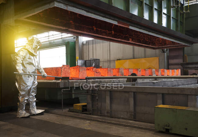 Человек в серебряном теплозащитном костюме работает на сталелитейном заводе. — стоковое фото