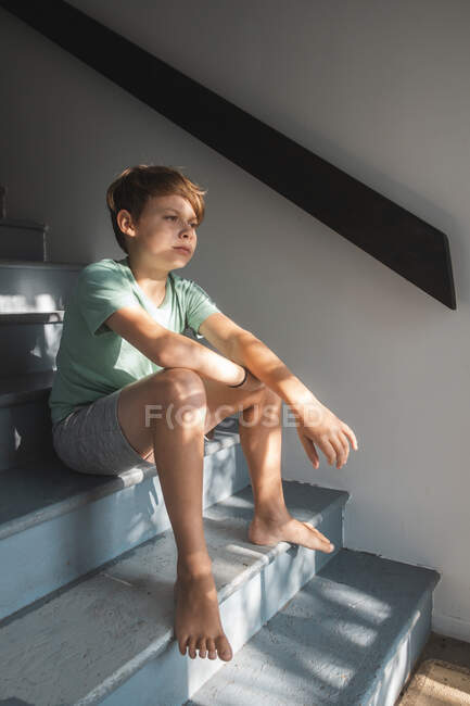Retrato de um menino de cabelos castanhos sentado em uma escada. — Fotografia de Stock