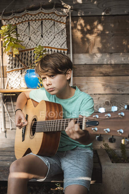 Retrato de niño de pelo castaño tocando la guitarra. - foto de stock