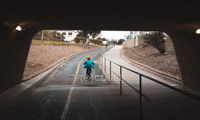 Vue arrière du garçon traversant le tunnel de la piste cyclable. — Photo de stock