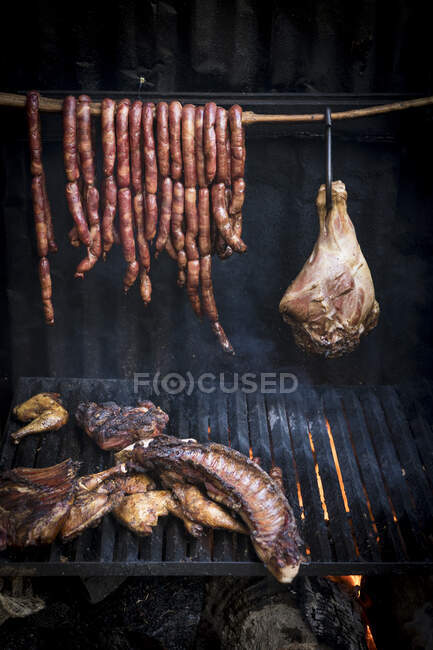 Carne affumicata e grigliata e salsicce appese a una rotaia. — Foto stock