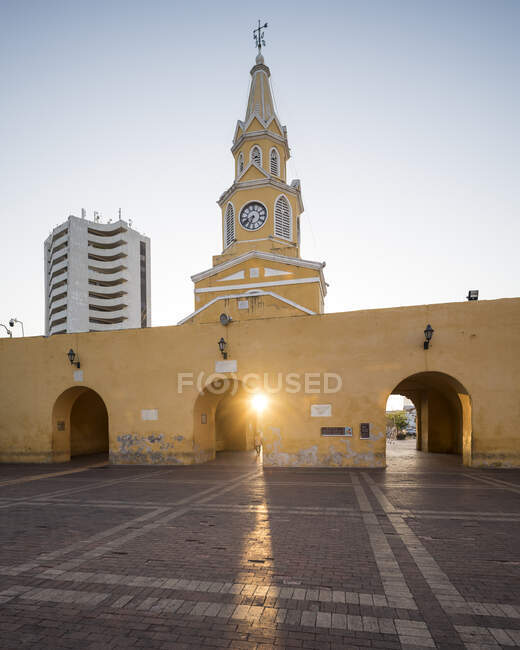 Часовая башня и городские ворота в старом городе, низкое солнце на мощеной площади. — стоковое фото
