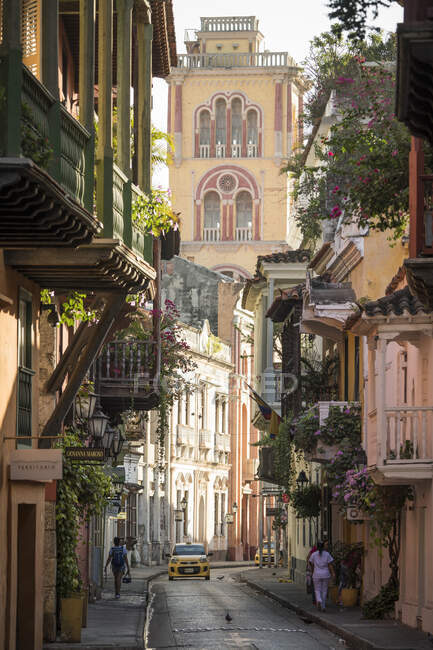 Вид на узкую улочку в Старом городе, элегантные исторические дома с балконами и высокой церковной башней — стоковое фото