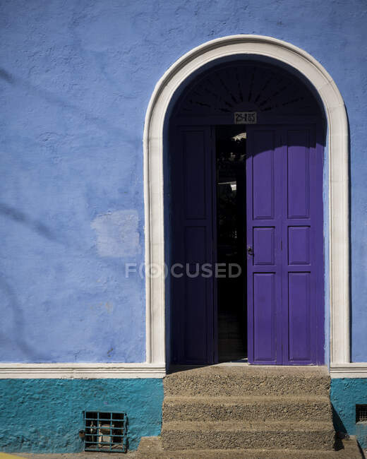 Colorida pared azul y puerta púrpura pintada en la Ciudad Vieja, Cartagena - foto de stock