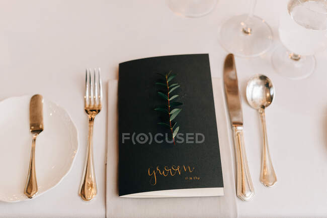 High angle close up of place setting at a wedding table, with black name card and silver cutlery. — Stock Photo