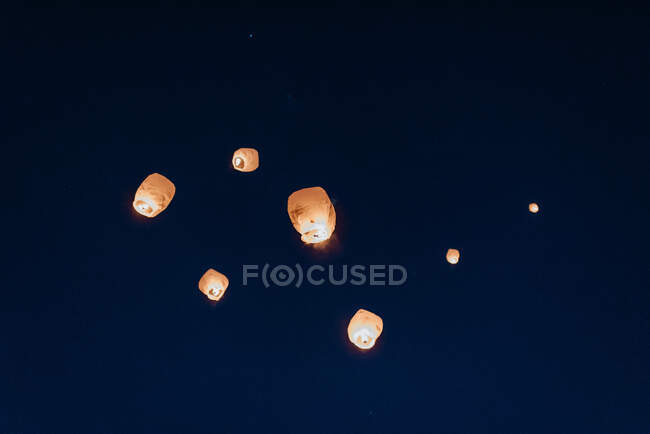 Vue à faible angle des lanternes chinoises libérées dans le ciel nocturne. — Photo de stock