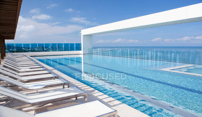 Lawn chairs by modern infinity pool — Stock Photo
