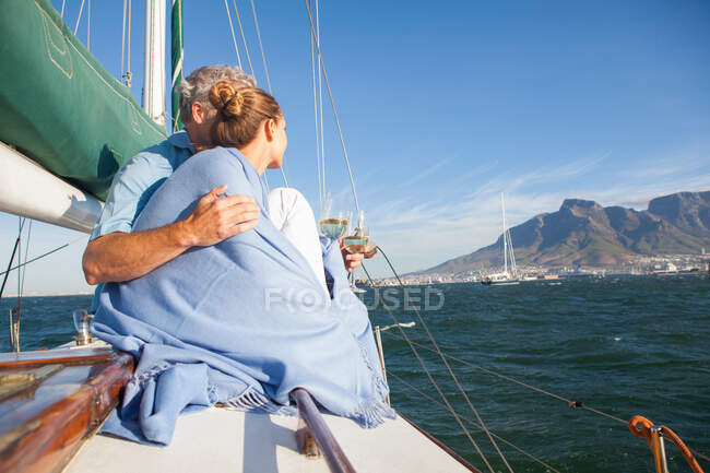 Couple on yacht with wine, woman wrapped in blanket — Stock Photo
