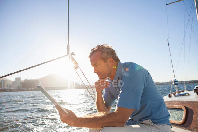 Человек на яхте с цифровым планшетом — стоковое фото