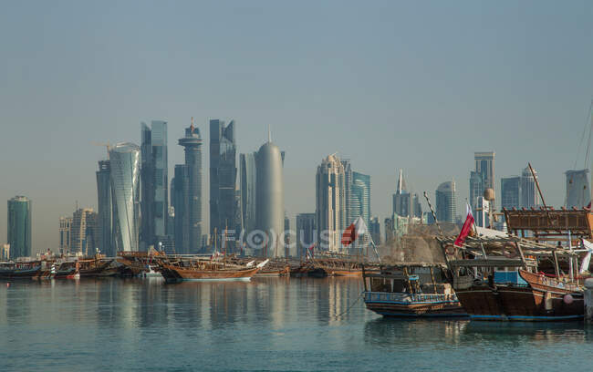 Barcos y el centro de Doha a través del agua, Doha, Qatar - foto de stock