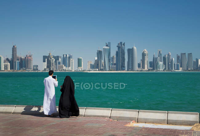 Homem e mulher olhando para arranha-céus sobre a água, Doha, Qatar — Fotografia de Stock