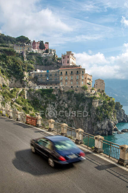 Coche en la carretera de la costa de Amalfi cerca del pueblo de Atrani, Campania, Italia - foto de stock