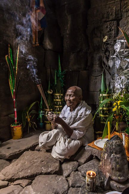 Monja devota, encendiendo incienso y ofreciendo oraciones en el Templo Preah Khan, Angkor, Camboya - foto de stock