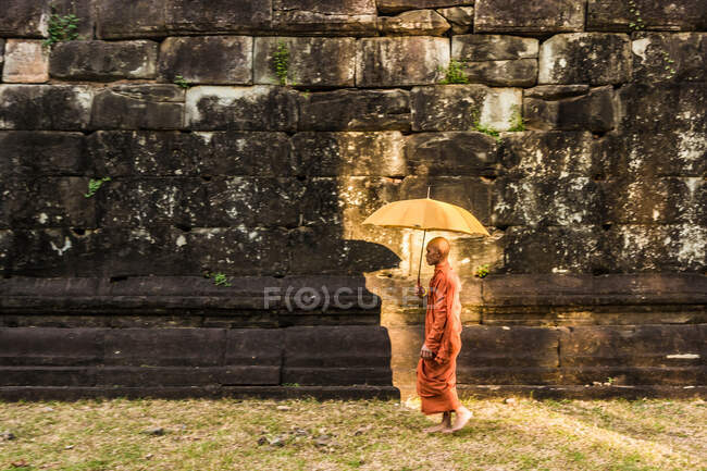 Moine avec parapluie, ruines du temple de Bakong (faisant partie du groupe Roluos de temples hindous pré-angkoriens), Bakong, Cambodge — Photo de stock