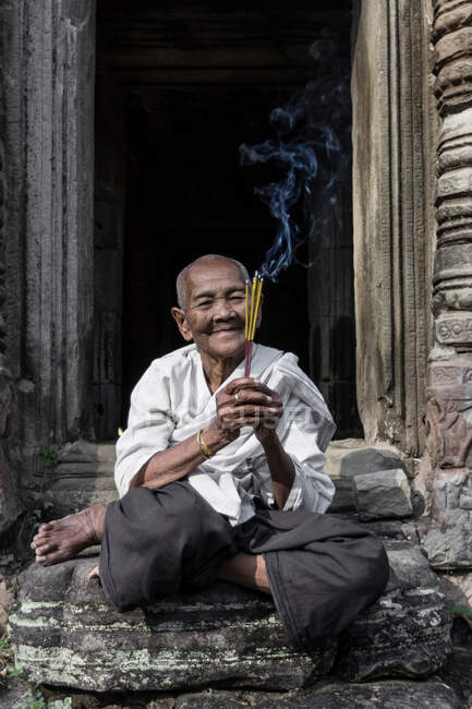 Monja devota, encendiendo incienso y ofreciendo oraciones en el Templo Preah Khan, Angkor, Camboya - foto de stock