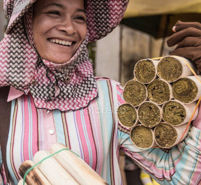 Mujer vendiendo bocadillos de arroz cocinados en tubos de bambú, Skuon, distrito de Cheung Prey, provincia de Kampong Cham, Camboya - foto de stock