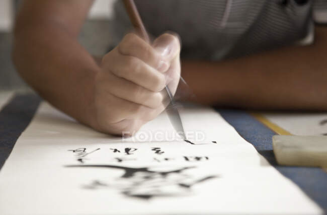 Каллиграф, пишущий китайские символы на свитке — стоковое фото