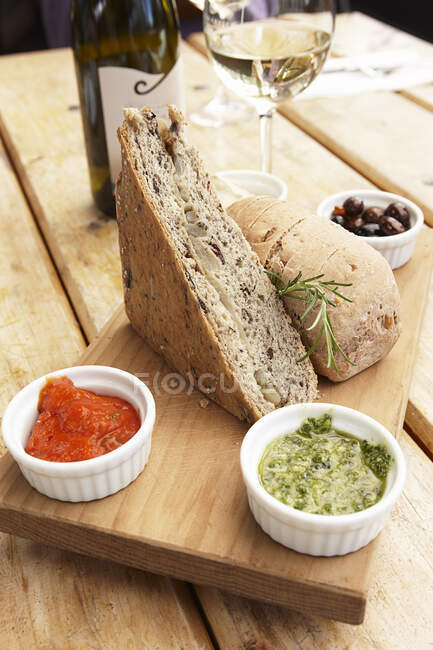 Bodegón con bocadillo de pan, salsas y vino blanco - foto de stock