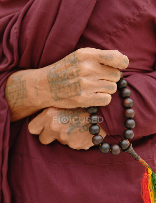 Primer plano del monje budista sosteniendo cuentas sagradas, Birmania - foto de stock