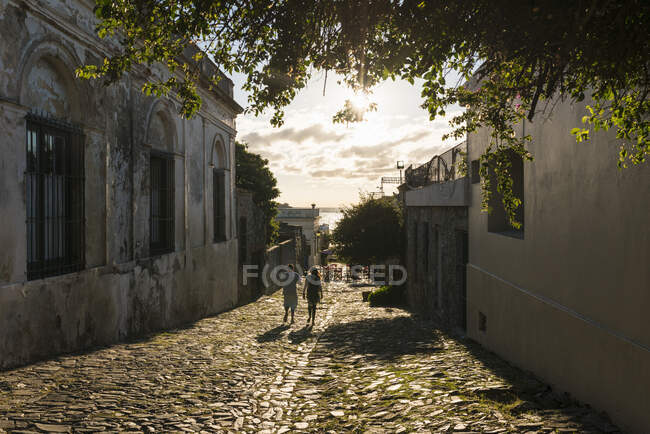 Duas pessoas passeando pela rua de paralelepípedos, Barrio Historico (Bairro Velho), Colonia del Sacramento, Colônia, Uruguai — Fotografia de Stock