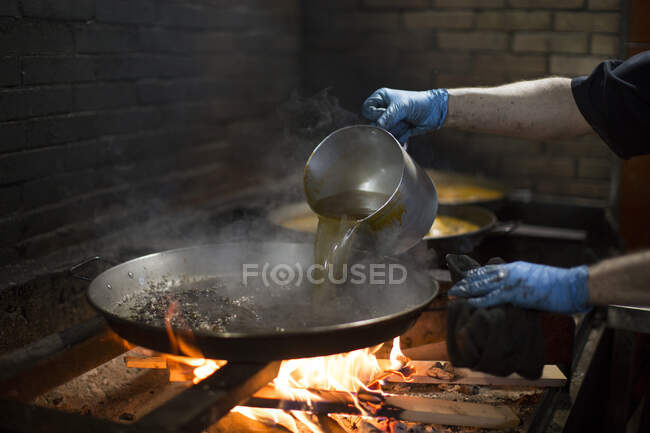 Человек, готовящий паэлью в огне — стоковое фото